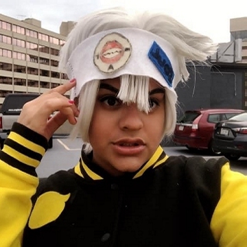 Mya in 2019, once again cosplaying Soul Evans with 2-tone jacket, white wig, & decaled headband.